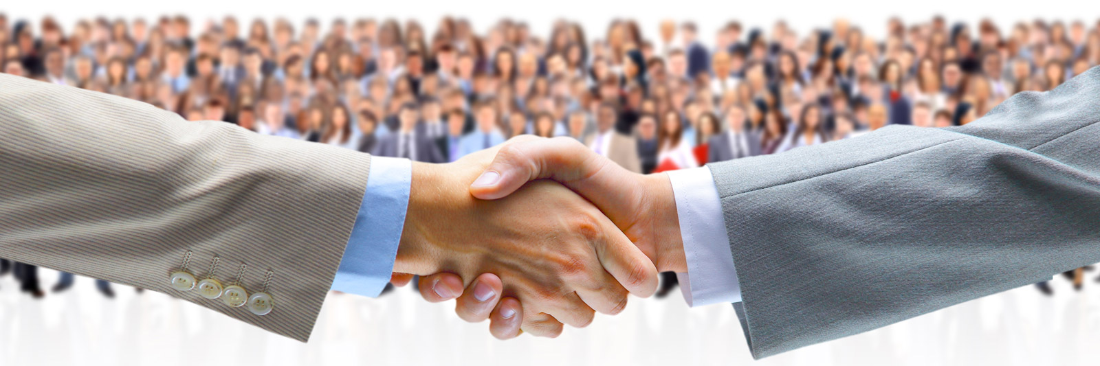 two hands shaking with a group of business people in the background